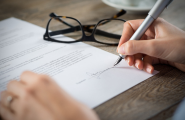 A hand signing a document