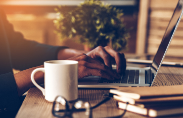 Coffee mug, glasses, and hands typing on computer